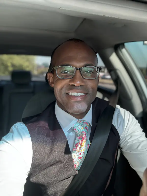 Maurice Howell smiles for a close portrait while seated in a car.